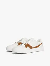 Zapatillas de corte bajo Tommy Hilfiger con diseño inspirado en el tenis, confeccionadas en piel napa blanca con paneles laterales de gamuza en color marrón. Presentan cierre con cordones, suela de goma y detalles de logo en bajo relieve.