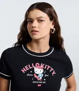 Remera negra de algodón con cuello redondo y bordes en contraste color blanco. Presenta estampa frontal de Hello Kitty en estilo skater con detalles en rosa y blanco.