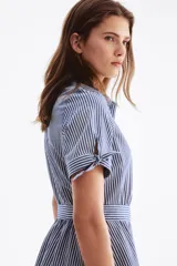 Vestido midi camisero con estampado de rayas verticales en tonos azul y blanco, cuello camisero, botonadura frontal y mangas cortas. Incluye un cinturón para anudar en la cintura y falda de corte acampanado.