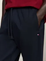 Pantalón de jogging azul marino, confeccionado en mezcla de algodón y poliéster, con cintura ajustable mediante cordón y puños elásticos en los tobillos. Presenta bolsillos laterales y un bolsillo trasero de ojal.