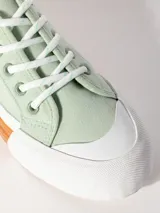 Zapatilla acordonada de textil color verde menta, con plataforma de goma bicolor en blanco y naranja con textura en relieve.