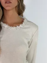 Remera de manga larga color azul, con cuello redondo adornado con un detalle de textura desflecada o peluda en el borde.