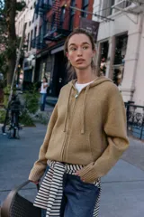 Sudadera de punto con capucha ajustable mediante cordones, manga larga y cierre frontal con cremallera. Presenta bolsillos delanteros y acabados en rib en puños y bajo.