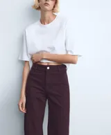 Jeans color bordó, de corte wide leg y tiro medio, con bolsillos laterales y traseros, y terminación sin dobladillo en los tobillos.