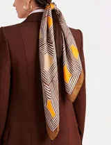 Pashmina cuadrada de satén con estampado geométrico de líneas y formas en tonos marrón, beige y amarillo.
