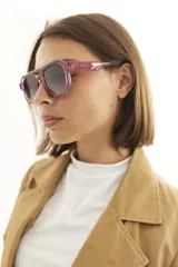 Lentes de sol de mujer con armazón grueso de policarbonato color rosa translúcido y lentes oscuros degradados. Diseño de montura geométrica con puente doble.