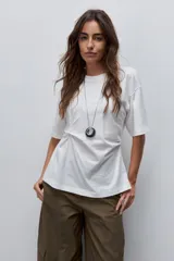 Remera de manga corta color blanco con cuello redondo y detalle de frunce lateral que aporta movimiento y una silueta entallada.