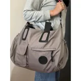 Bolso deportivo multifunción color negro, con diseño liso, compartimento principal con cierre, bolsillo frontal con solapa y bolsillo frontal con cierre. Cuenta con doble asa de mano y correa de hombro ajustable y extraíble. Incluye detalle de logo circular en la parte inferior.