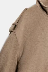 Cazadora de corte bomber en color marrón claro, con cuello subido, mangas largas con trabillas en los hombros, y cierre frontal oculto con cremallera y botones a presión.