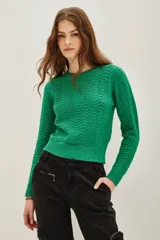 Sweater de punto color verde con diseño de ondas en relieve y sutiles destellos de lentejuelas integradas. Presenta cuello redondo, mangas largas y puños acanalados.