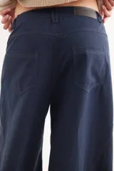 Pantalón de tiro medio con diseño de pierna ancha y cortes curvos que aportan movimiento. Presenta cintura ajustada, bolsillos delanteros y bolsillos plaque en la parte trasera.