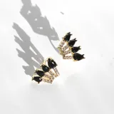 Par de aros dorados con cristales claros y negros en forma de lágrima.
