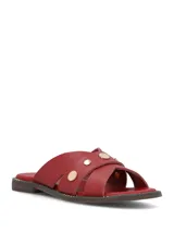 Sandalias planas de cuero rojo con tiras cruzadas y tachas metálicas doradas.
