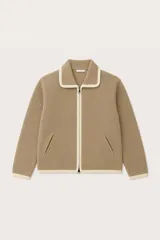 Saco de punto color beige con cierre frontal, cuello tipo polo y detalles de ribete en color crema en el cuello, puños, ruedo y a lo largo del cierre. Cuenta con dos bolsillos laterales tipo ojal.