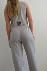 Chaleco a rayas verticales azules y blancas con cuello en V, cierre con botones y bolsillos frontales.