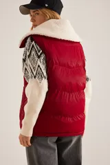 Chaleco puffer rojo con cuello de sherpa color crema, cierre frontal con cremallera y bolsillos laterales.