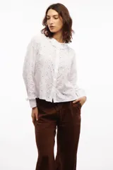 Camisa de algodón blanca con bordado inglés de motivos florales, cuello con volados y cierre frontal de botones.