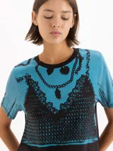 Remera de manga corta con cuello redondo, en tonos celeste y negro, con estampado frontal simulando un corset de encaje y collares de cadenas.