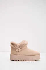 Bota corta tipo moon boot color beige, confeccionada en gamuza sintética con interior y borde superior de piel sintética. Presenta una suela de plataforma plana y una tira decorativa con hebilla metálica en el lateral.