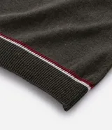 Camisa polo de manga corta color verde oliva, confeccionada en tejido de punto, con cuello y puños con ribetes contrastantes en blanco y rojo.