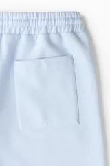 Short de felpa celeste de corte regular fit, con cintura elástica y cordón ajustable. Cuenta con bandas laterales blancas con el logo de Lotto repetido, bolsillos laterales y el logo de la marca bordado en una pierna.