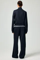 Pantalón de corte holgado en punto pesado con leve brillo, color negro. Modelo con elástico revestido en la cintura, bolsillos al bies y piernas rectas con pliegues cosidos.