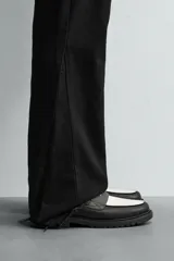 Mocasín de cuero marrón oscuro con antifaz en tono camel. Presenta horma redonda y suela track gruesa de goma negra.