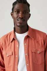 Camisa de manga larga color ladrillo, con cuello clásico, cierre frontal con botones a presión, dos bolsillos con solapa abotonada en el pecho y canesú en punta en la espalda.