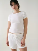 Remera de manga corta color blanco con textura pointelle, corte entallado y cuello redondo con detalle de borde sutilmente ondulado.