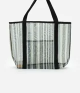 Bolso de playa rectangular de poliéster con rayas verticales en tonos de verde, gris y blanco. Tiene asas de algodón negras y un bolsillo externo.