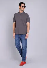 Remera tipo polo de manga corta en color gris oscuro, con cuello clásico y cierre frontal de dos botones. Presenta un pequeño logo bordado en el pecho.