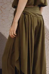 Pantalón globo de tiro alto color verde militar en tejido satinado con leve brillo. Presenta cintura elástica revestida, sección cruzada que se ata en un lateral con caída fluida y bajos elásticos ajustados.
