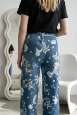 Jean de corte recto y tiro alto con estampado floral en tonos claros sobre base azul denim. Cuenta con cierre frontal y bolsillos laterales.
