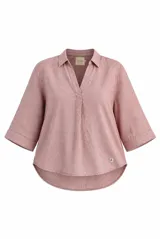 Blusa azul de lino con cuello camisero, escote en V y mangas tres cuartos con vuelta. Presenta un diseño holgado con dobladillo redondeado y un pequeño parche con logo bordado en el lateral inferior.