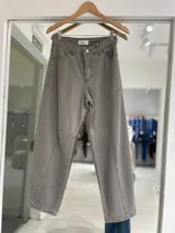 Jean de corte baggy en color gris, con diseño de costuras verticales y paneles en las piernas. Cuenta con cierre de botón metálico y bolsillos laterales.