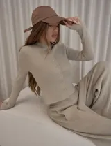 Conjunto de dos piezas compuesto por un cardigan entallado de tejido de punto con botones frontales y un pantalón de tiro medio con corte amplio y relajado. El diseño presenta una estética minimalista y versátil.