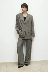 Conjunto sastrero color gris con finas líneas verticales blancas, compuesto por un blazer oversize con solapas de muesca y un pantalón de vestir de corte recto.