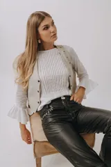 Camisa blanca de manga larga con puños con volados, cuello redondo y detalle de pliegues frontales.
