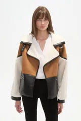 Chaqueta estilo aviador o biker, con paneles de color marrón (simil gamuza), negro (simil cuero acolchado) y blanco (simil borrego/sherpa). Presenta cuello solapa ancho forrado en blanco, detalles de hebillas negras en los hombros y cierres metálicos en la parte delantera.