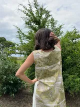 Vestido midi de corte evasé con estampado de hojas en tonos verdes y beige.
