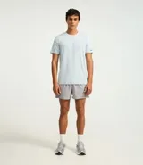 Remera deportiva de hombre con tecnología dry fit, cuello redondo y manga corta. Presenta un diseño liso en color beige con una pequeña etiqueta decorativa en el dobladillo.