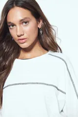 Remera de manga corta con silueta relajada y costuras a la vista en color blanco que contrastan sobre el tejido negro. Presenta un diseño moderno con terminaciones destacadas.