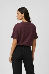 Remera de algodón color marrón con cuello redondo y mangas cortas. Presenta un estampado frontal con ilustraciones de dos copas de cóctel decoradas con lazos.