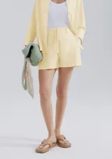 Shorts de lino color amarillo pastel, de tiro medio con presillas y cordón ajustable en la cintura.