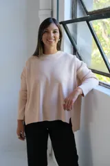 Sweater de tejido de punto color crudo, con cuello redondo, mangas largas y diseño holgado con aberturas laterales en el ruedo.