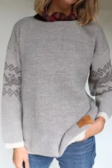 Buzo oversize tejido con diseño jacquard de un grifo en la espalda y detalles geométricos en las mangas. Presenta cuello redondo y puños acanalados.