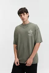 Remera oversize de algodón con efecto acid wash, color blanco hueso. Estampado grande en la espalda con un diseño circular que incluye una serpiente enroscada, texto "MISTRAL REG", "LOS ANGELES", "CALIFORNIA", "VINTAGE DENIM", "REGISTERED" y "TM 76".