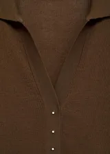 Jersey de punto fino color marrón, con cuello camisero, manga corta y cierre frontal con botones pequeños.
