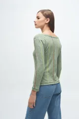 Remera de manga larga en color gris melange, con cuello redondo y costuras decorativas verticales en contraste de color verde lima y blanco.