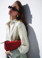 Camisa cruzada de ramio en color crudo, con cuello camisero, escote en V y mangas largas con puños anchos abotonados. Cuenta con un diseño envolvente con detalle de lazo lateral.